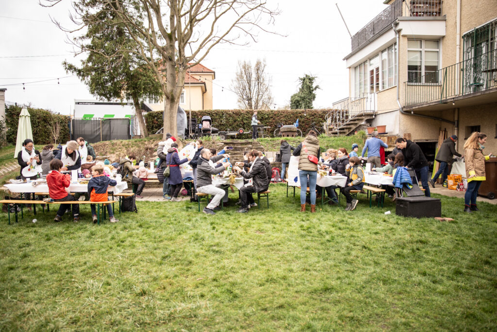 Gent asseguda en taules en un jardí, menjant calçots